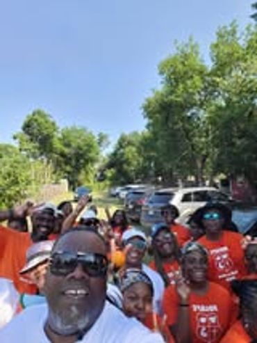 Group selfie of people outdoors wearing matching orange shirts.