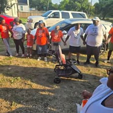 Group of people standing outdoors with a stroller in front.