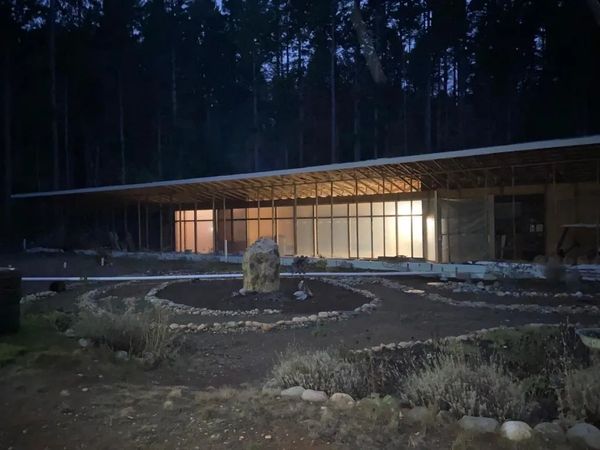 The south face of the Earthship with the greenhouse lit up with lights from within the building.