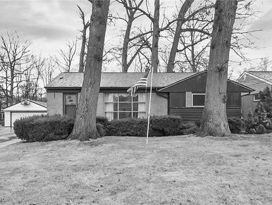 Single-story house with an American flag in the front yard during winter.