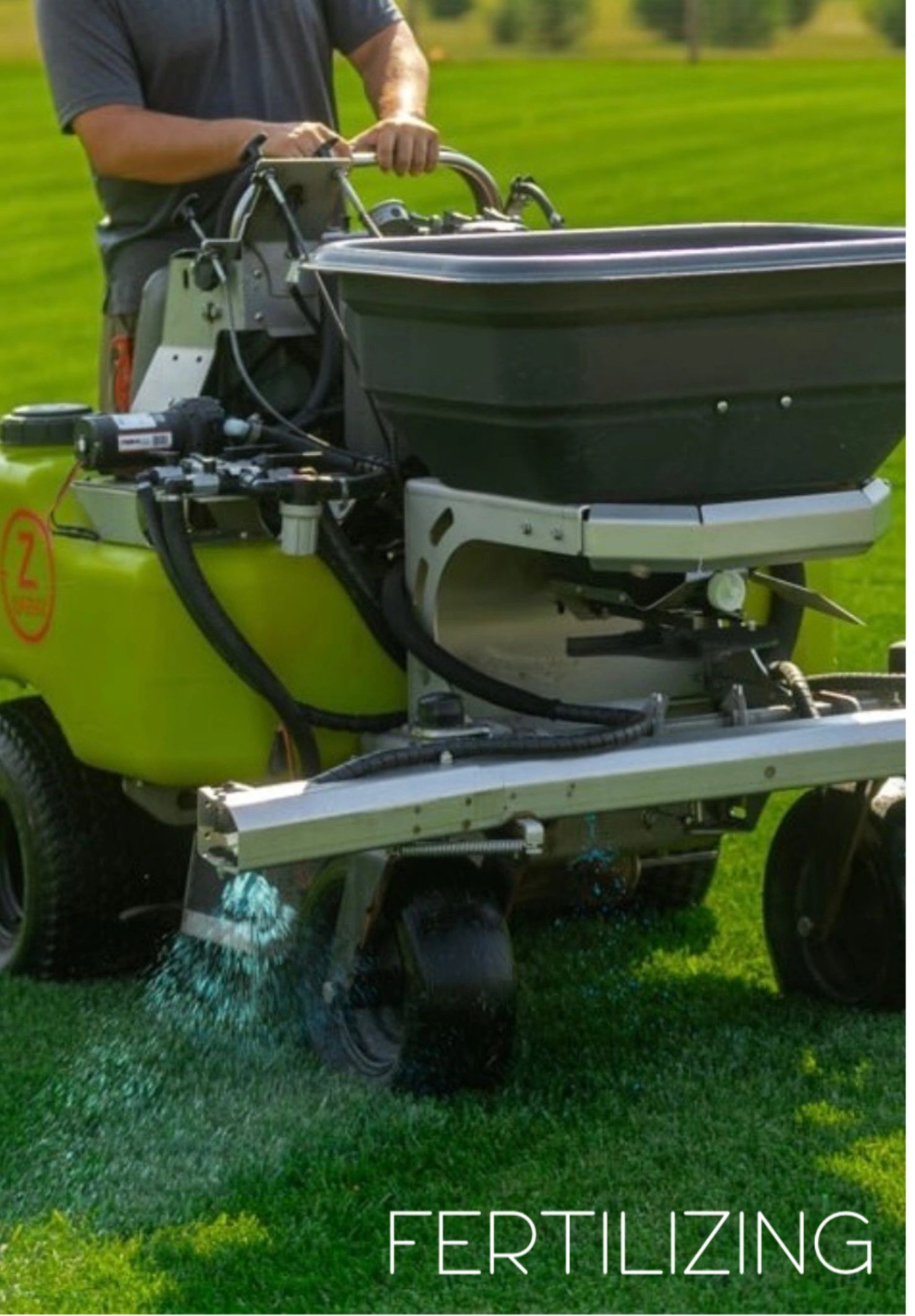 Person using a machine to fertilize a green lawn.
