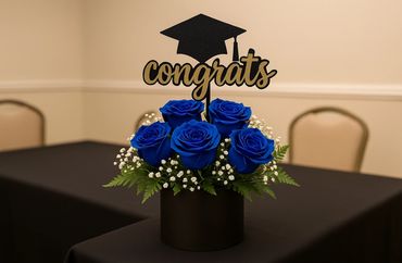 Blue roses with a graduation-themed 'congrats' decoration.