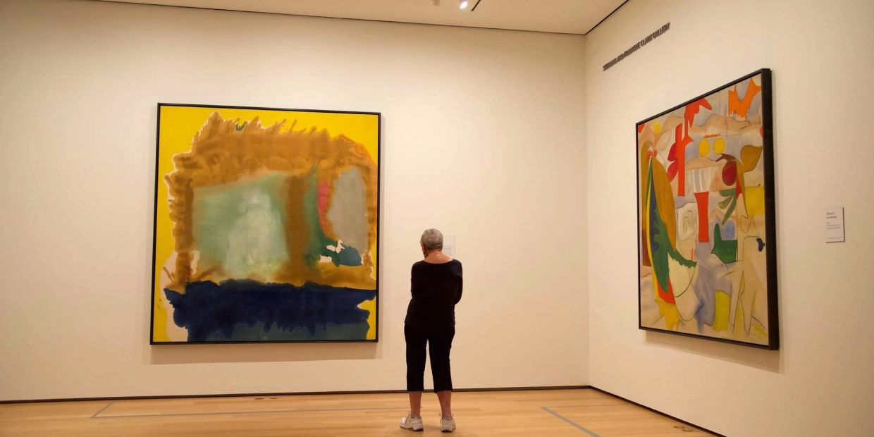 Person viewing abstract paintings in an art gallery.