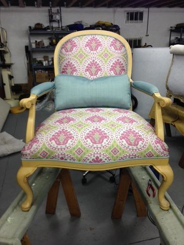 Ornate vintage chair with pink and green patterned upholstery and light blue cushion.