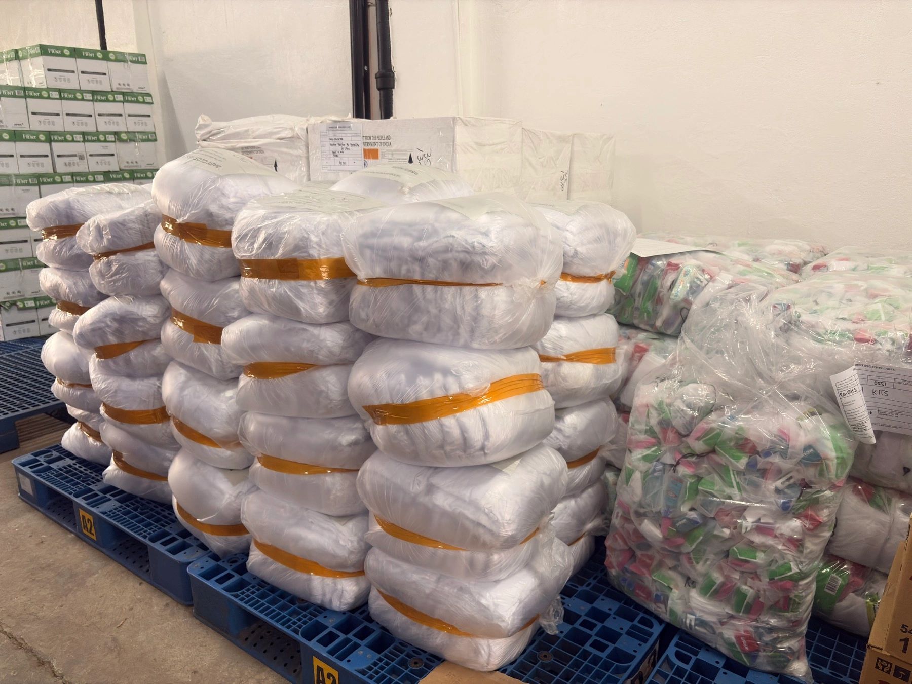 Stacked packaged items on pallets in storage.