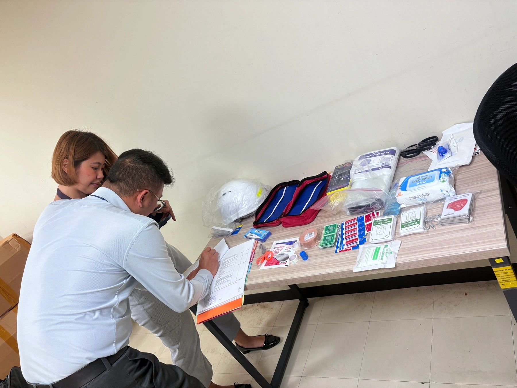 Two people examining medical supplies on a table.