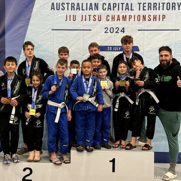 Young athletes on the podium at a Jiu Jitsu championship.