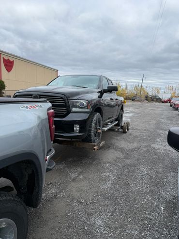 Black pickup truck being towed with a flat tire on a cloudy day.