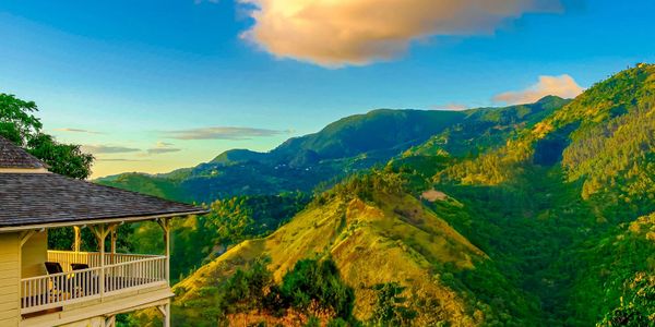 A scenic mountain view at sunset with a wooden house balcony.