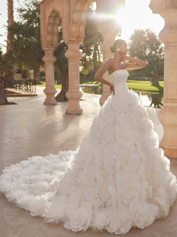 Bride in an elegant strapless gown with floral details and a long train.