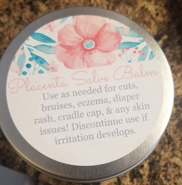 Tin of Placenta Salve Balm with floral design and usage instructions.