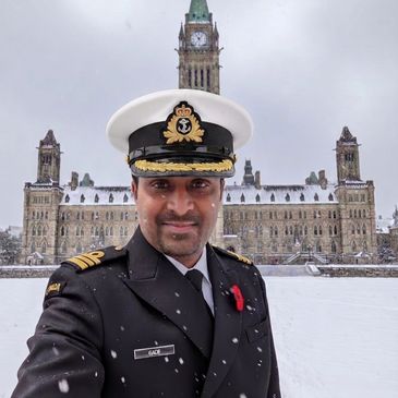 Naval officer taking a snowy selfie in front of a historic building.