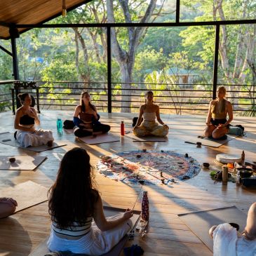 Group yoga meditation session on a wooden deck.