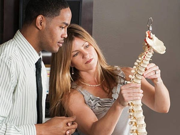 Two professionals examining a spinal model closely.