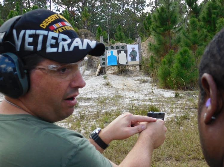 Veteran instructing on handgun shooting at an outdoor range.