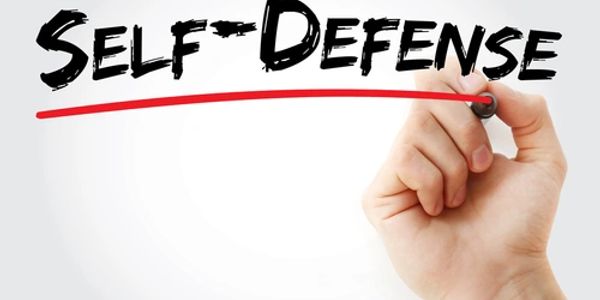 Hand underlining the words 'Self Defense' with a red marker.