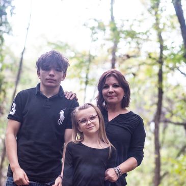 Mother, daughter, and son portrait wearing black shirts in the woods.