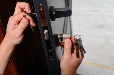 Hands installing a door lock with keys in hand.