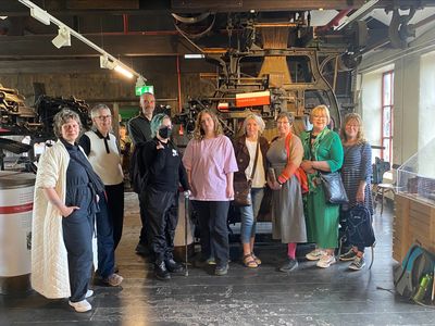 A group of artists stand in front of a Jacquard loom in Leeds Industrial Museum.