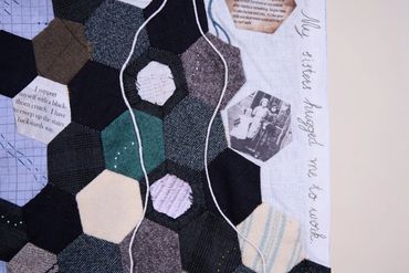 Patchwork in hexagons of cotton and wool fabric. On left the title of this artwork is embroidered