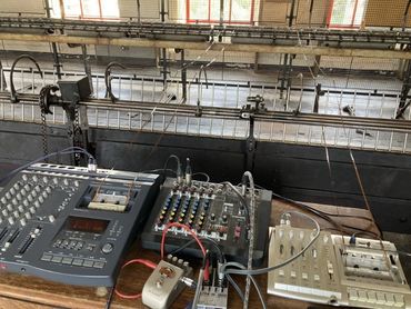Sound mixing equipment on a table opposite the spinning mule carriage in Leeds Industrial Museum