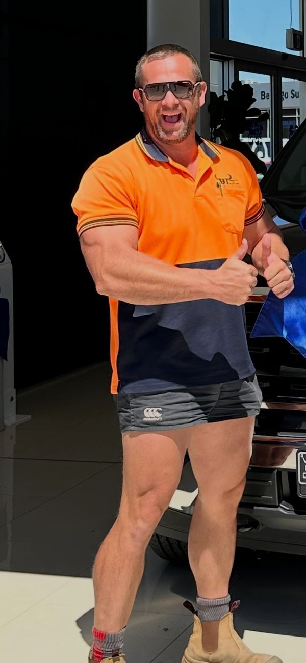 Man in orange shirt and sunglasses giving thumbs up with a big smile.
