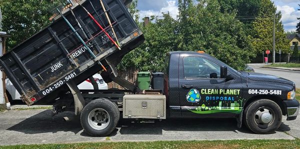 A Clean Planet Disposal truck with raised dump bed filled with tools.