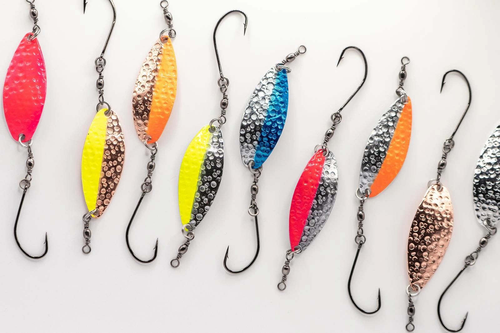 Colorful fishing lures with hooks arranged on a white surface.