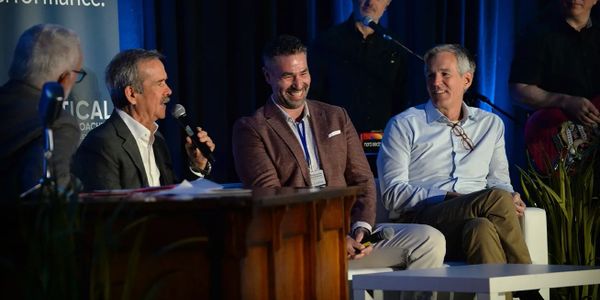 Three men engaged in a lively panel discussion at a conference.