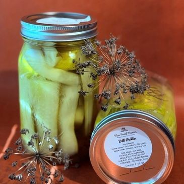 Jars of homemade dill pickles with dill flowers.
