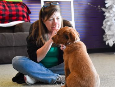 Sandy, founder and board president of Anything Is Pawsable, seated on the floor while training an AI