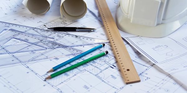 Architectural blueprints with drafting tools and a safety helmet.