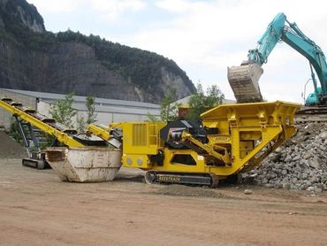 Yellow construction machinery with conveyor belts at a rocky site.
