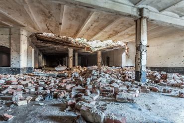 Interior of a dilapidated building with debris and broken bricks scattered on the floor.
