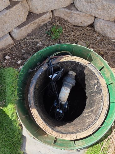 Open irrigation valve box with pipes and cables.