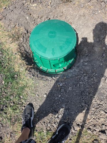 Green underground water valve box on dirt.