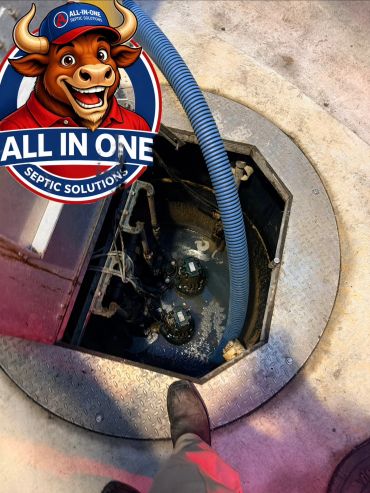 Open septic tank with blue hose and worker's boots nearby.