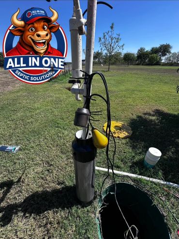 Septic system pump installation in a grassy field with clear sky.