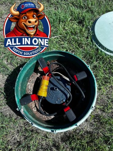 Open septic tank with equipment inside, grass around.