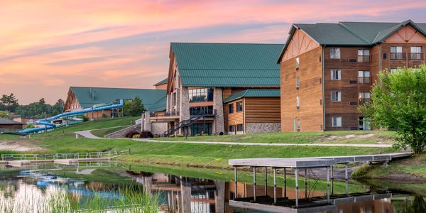 Resort buildings reflecting on a calm pond during sunset.