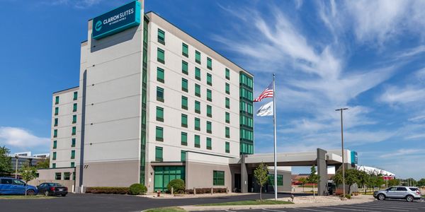 Clarion Suites hotel building under a clear blue sky with flags flying.