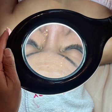 Person's forehead and closed eyes magnified by a round lens.