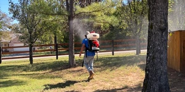 Person spraying outdoors with backpack sprayer.