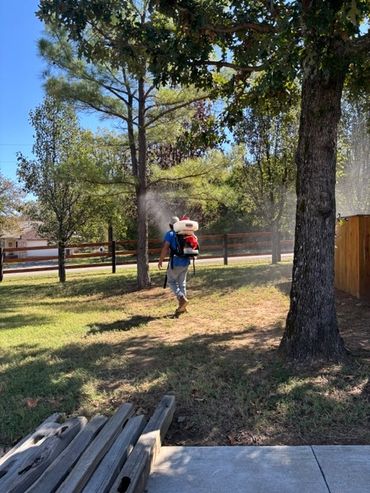 Person spraying outdoors with backpack sprayer.