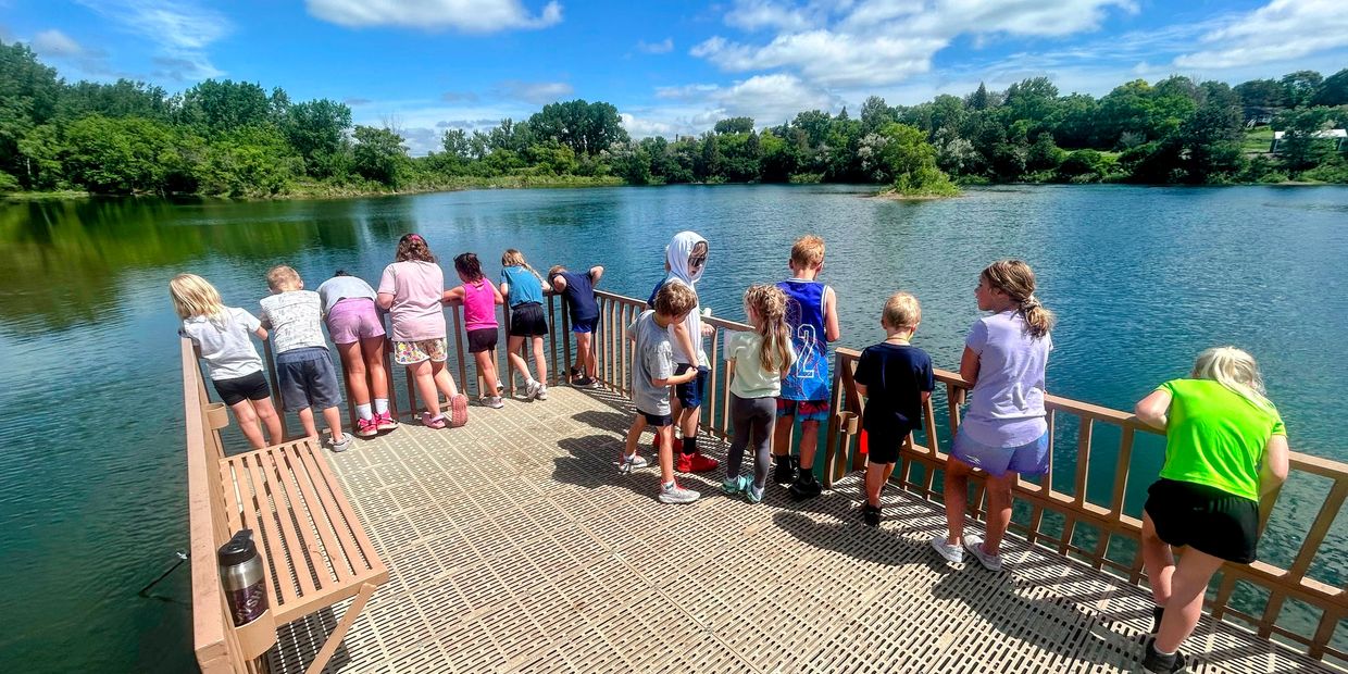 Children standing on a dock looking into the water.
