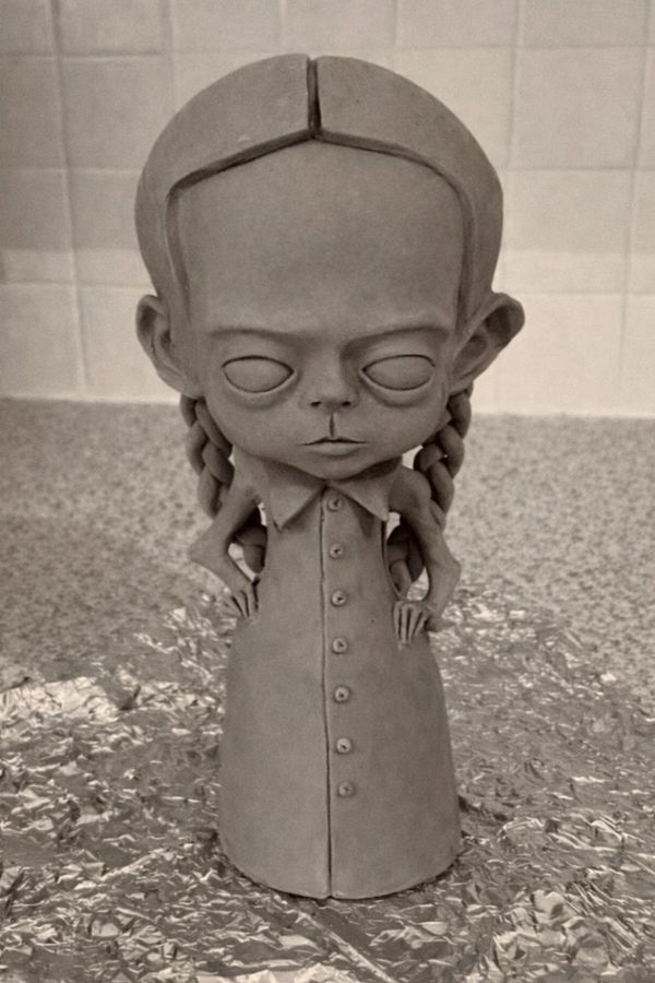 Clay sculpture of a girl with braided hair and closed eyes.