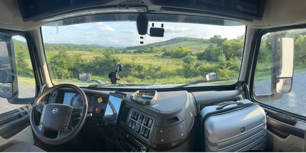 View from inside a Volvo truck cabin overlooking a green landscape.