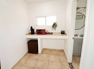 Small kitchenette with a red microwave, coffee machine, and mini fridge.