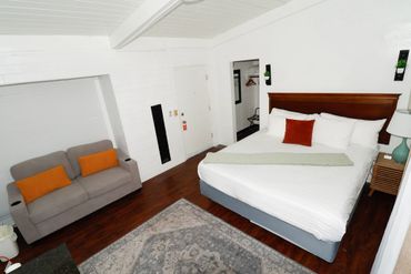 Cozy hotel room with a large bed, sofa, and wooden floor.