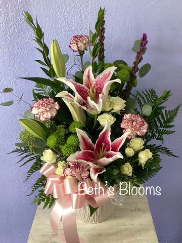 Elegant floral arrangement with lilies, carnations, and greenery in a white vase.